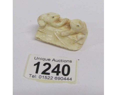 An ivory netsuke being 2 frogs on a seed