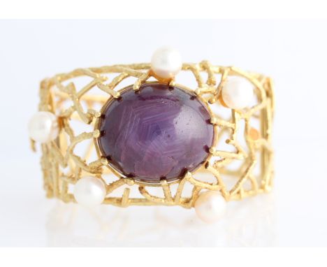A 1970s 18ct yellow gold star ruby and pearl bangle, featuring a central oval star ruby cabochon, measuring approx. 28x24x18c