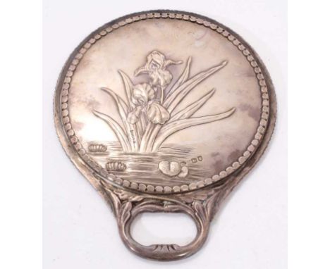 Late Victorian silver mounted hand mirror of circular form, with integral handle and decorated on the reverse with raised ima