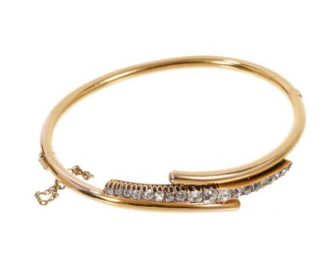 Late 19th Century diamond hinged bangle with a line of graduated cushion shape old cut diamonds in claw setting on 14ct gold 