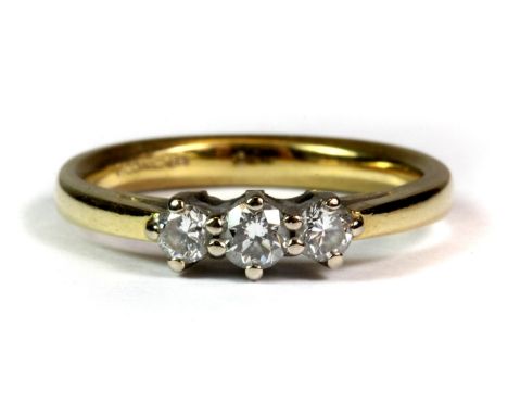 An 18ct yellow gold ring set with three brilliant cut diamonds (L).