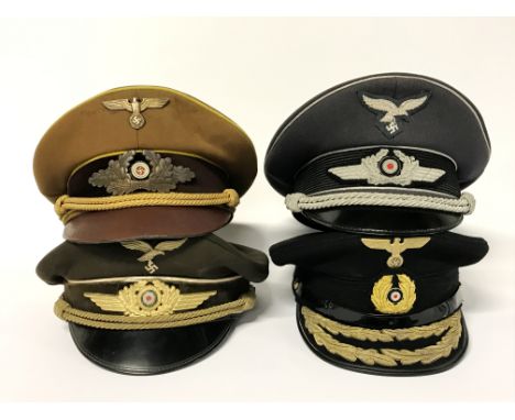 Four German Army officers caps bearing Nazi insignia.
