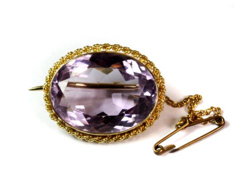 A yellow metal (tested minimum 9ct gold) brooch set with a large oval cut amethyst, L. 2.6cm.