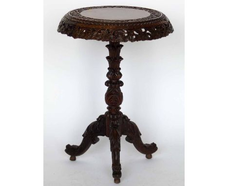 A Burmese carved hardwood tripod table, the circular tip-top with a foliage rim on an ornate central column and three spreadi