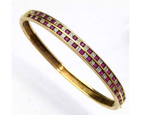 375 gold ruby and diamond bangle, the hinged half hoop set with two channels of alternating stones, 13.2g gross.