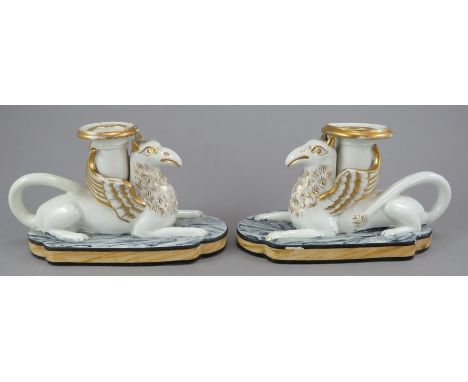 A pair of early nineteenth century porcelain winged griffin candle sticks with painted marbling to base and gilded highlights