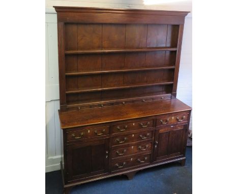 A George III oak dresser fitted two cupboard doors and a central bank of drawers with simple rack above. Raised on bracket su