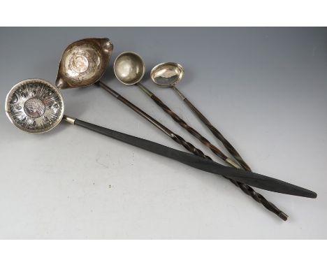 A small collection of silver and white metal toddy ladles one with Geo II coin inset bowl and twisted ebony haft. Together wi