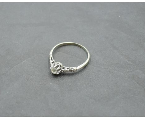 A diamond solitaire ring of dainty form, approx 0.25ct in a raised claw mount having diamond set shoulders on a white metal l