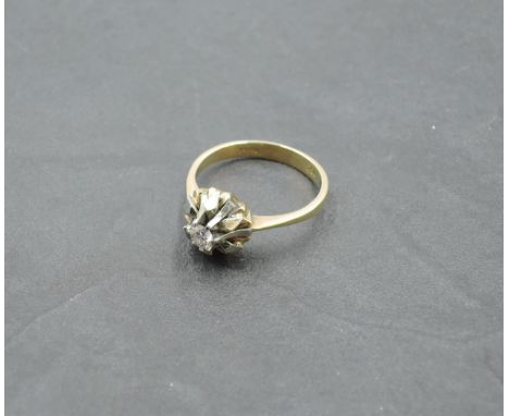 A diamond solitaire dress ring, approx 0.125ct in a stylised white and yellow metal mount to knife blade shoulders on a yello