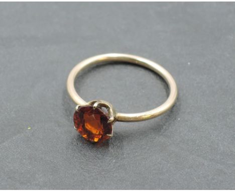 A small solitaire dress ring having a hessonite garnet style stone in a 6 claw setting on a rose gold loop tested as 9ct, siz