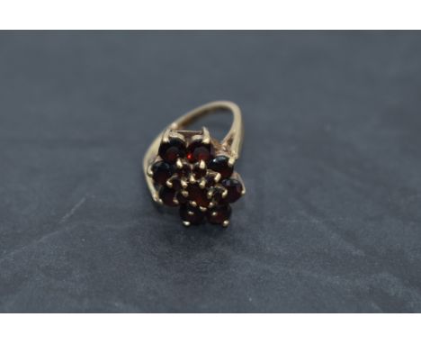 An oval garnet triple cluster dress ring having a raised basket mount on a 9ct gold loop, size O &amp; approx 5.4g