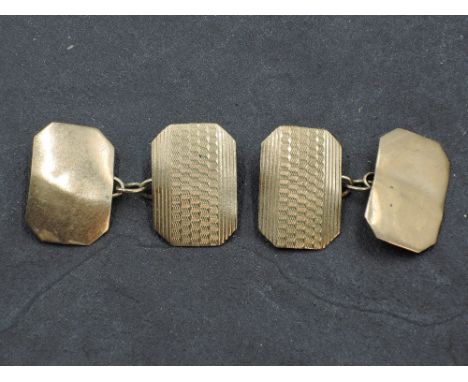 A pair of yellow metal cufflinks stamped 9ct of canted oblong form having engine turned decoration and chain connectors, appr