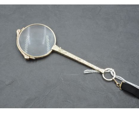 An early 20th century yellow metal lorgnette, of traditional design with scroll engraved tapering square section 'handle', ma