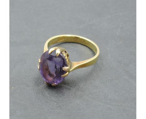 An Oriental oval amethyst dress ring in a raised claw mount on a 14ct gold loop bearing possibly Chinese marks, size N &amp; 