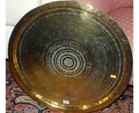 An Eastern engraved brass circular tray of dished form, dia. 60cm