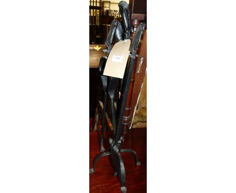 A set of three black painted wrought iron fire tools on stand
