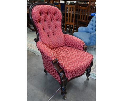 A Victorian mahogany framed button back armchair on turned legs with brass casters 