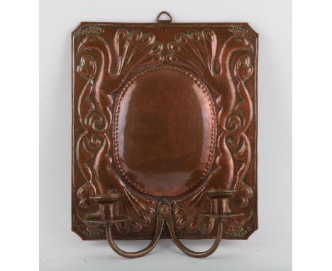 Arts and Crafts copper twin branch girandole type wall light or sconce, the rectangular back repousse decorated with peacocks