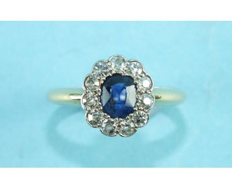 A sapphire and diamond cluster ring set an oval sapphire, within a border of eleven 8/8-cut diamonds, in 18ct yellow and whit