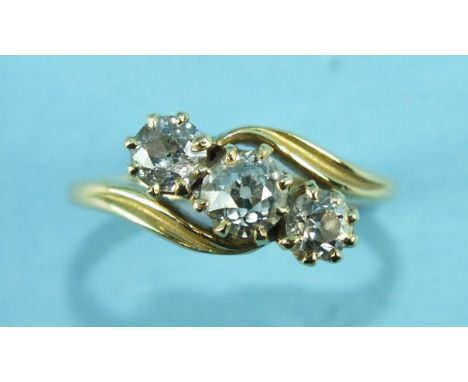 A three-stone diamond cross-over ring, the old brilliant-cut diamonds claw set in 18ct yellow gold mount, size M, 2.9g.