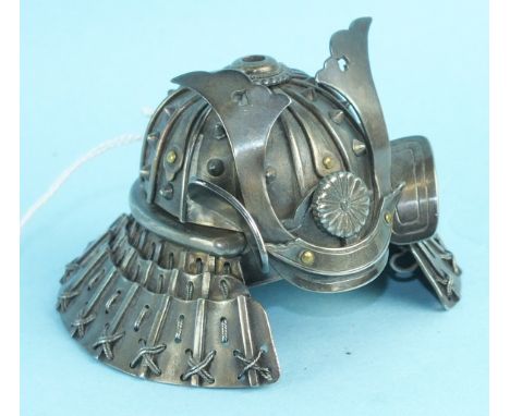 A white metal model of a kabuto (samurai helmet), the upper part hinged to reveal a small compartment, 4.5cm high, 6.5cm diam