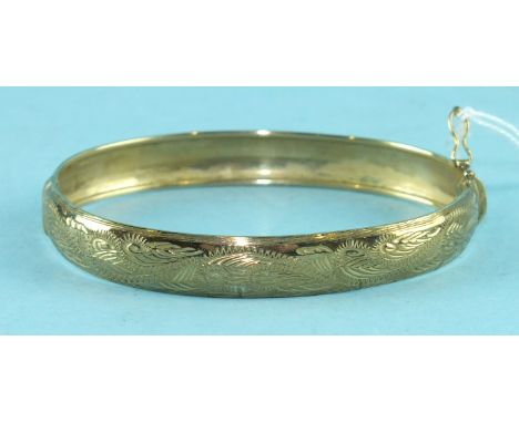 A 9ct gold hinged bangle with engraved decoration, 6.5cm across, 7.6g.
