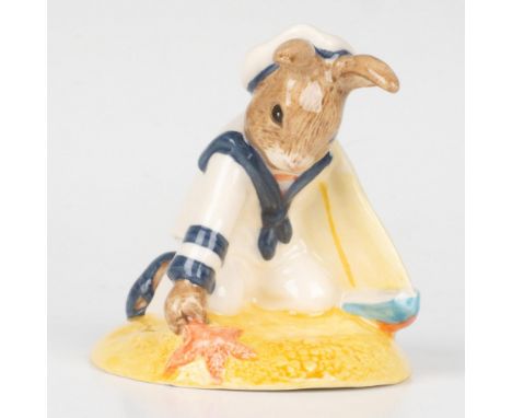 A figure of a bunny dressed in naval uniform, playing in the sand with a boat and starfish. Bunnykins of the Year 1997. This 