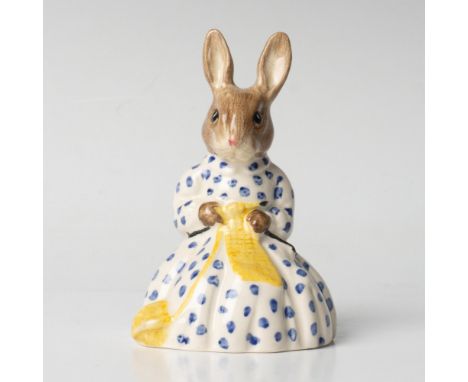A female bunny wearing a white dress, adorned with blue flowers, and she is knitting a yellow scarf. Royal Doulton backstamp.