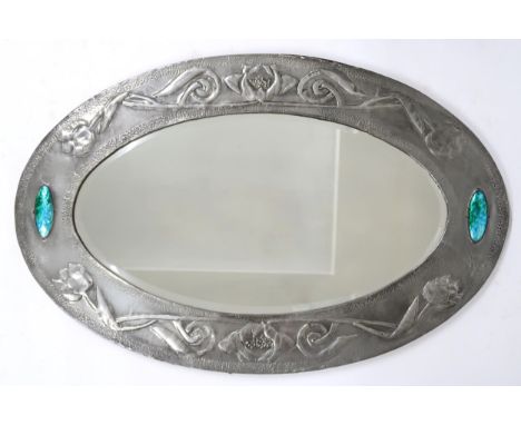 A GLASGOW SCHOOL ARTS AND CRAFTS PEWTER FRAMED MIRROR of oval shape with relief decoration of flowers and scrolling foliage w