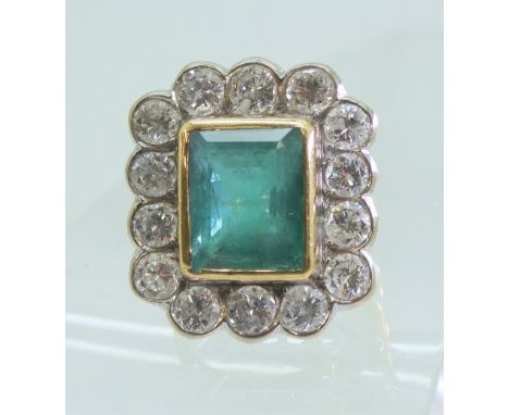 AN EMERALD & DIAMOND CLUSTER RING this substantial ring is set with a large step cut emerald with the dimensions of 13mm x 1m