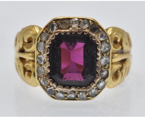 An antique garnet and diamond cluster ring. The ring set with an emerald cut garnet framed by a border of rose cut diamonds h