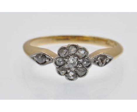 An 18ct gold and diamond cluster ring. The ring set with a cluster of rose cut diamonds with rose cut diamond accent shoulder