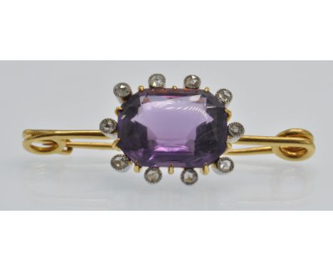 An 18ct gold amethyst and diamond brooch pin . The brooch set with a large oval cushion cut amethyst surrounded by bezel set 