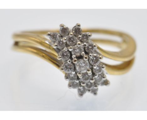 A hallmarked 18ct yellow gold and diamond cluster ring. The ring set with a raised scrolled diamond cluster to a pierced shan