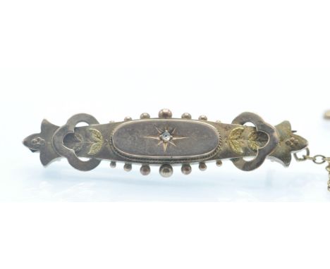 A Victorian hallmarked 9ct gold and diamond brooch pin. The brooch set with a diamond chip in a star setting flanked by etche