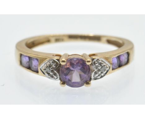 A hallmarked 9ct gold amethyst and diamond ring. The ring set with a central round mixed cut amethyst flanked by illusion set