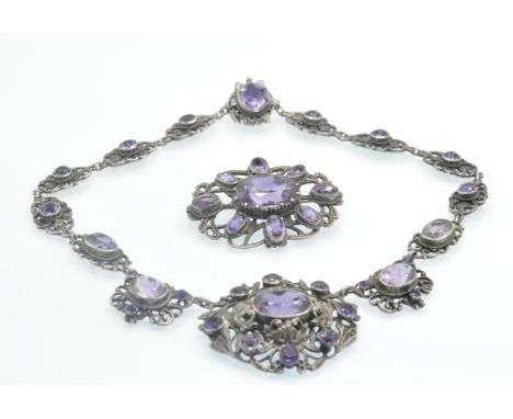 An early 20th century silver and amethyst choker necklace and brooch. The necklace having pierced foliate decoration set with