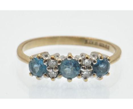 A hallmarked 9ct gold diamond and topaz ring. The ring set with three round mixed cut blue topaz having four single cut diamo