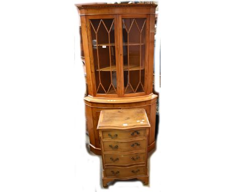 A reproduction yew wood veneered bowfronted free standing corner cabinet with two astragal glazed doors above panelled cupboa