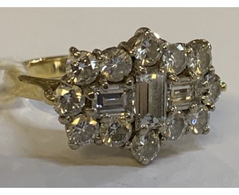 An 18ct yellow gold and diamond cluster ring, centred with three baguette cut stones within a border of twelve round brillian