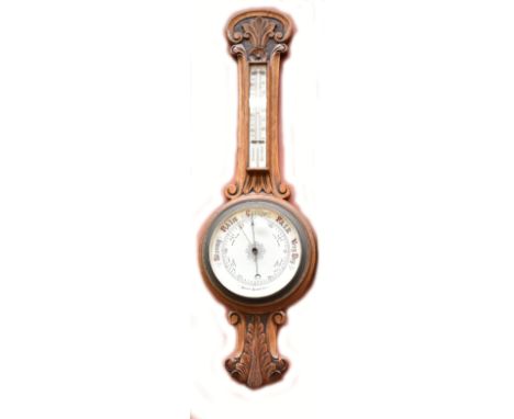 An early 20th century carved oak aneroid barometer, length 88cm.
