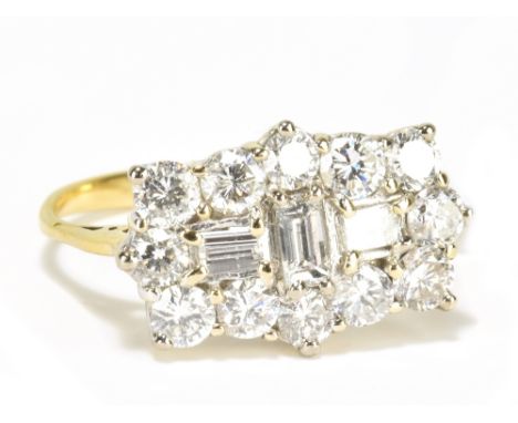 A yellow metal diamond ring with three central rectangular diamonds within a border of twelve round brilliant cut stones, siz