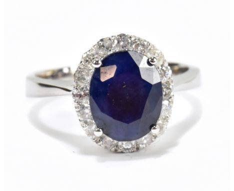 A white metal diamond and sapphire cluster ring, the modified brilliant cut sapphire weighing approx 3.55ct surround by sixte
