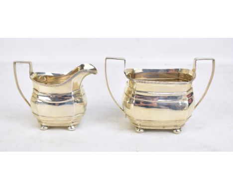 GEORGE NATHAN &amp; RIDLEY HAYES; a George V hallmarked silver twin handled sugar bowl and cream jug with reeded detail, both