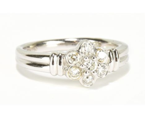 An 18ct white gold seven stone diamond and floral cluster ring totalling approx 0.33cts, size M 1/2, approx 4.8g.