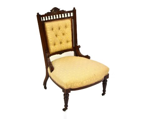 A Victorian nursing chair, with button back panel, raised on tapering column supports terminating on brass castors.