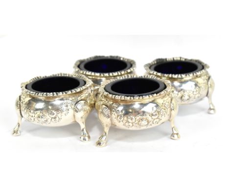 A set of four Victorian hallmarked silver circular salts with embossed floral swags raised on three hoof feet, London 1877, d