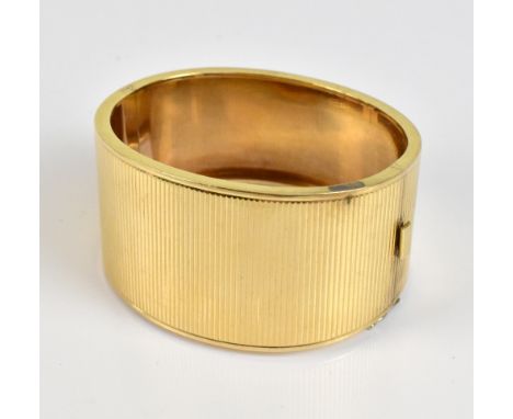 A yellow metal engine turned decorated hinged snap bangle of tapering broad form, internal width 5.6cm, approx 49g.