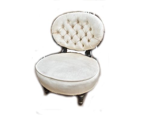 An ebonised button back upholstered nursing chair raised on turned front legs.